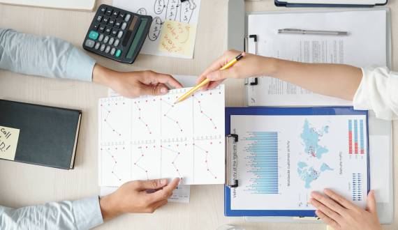 Hands of businesswoman giving report to colleague and explaining every line chart meaning, view from above